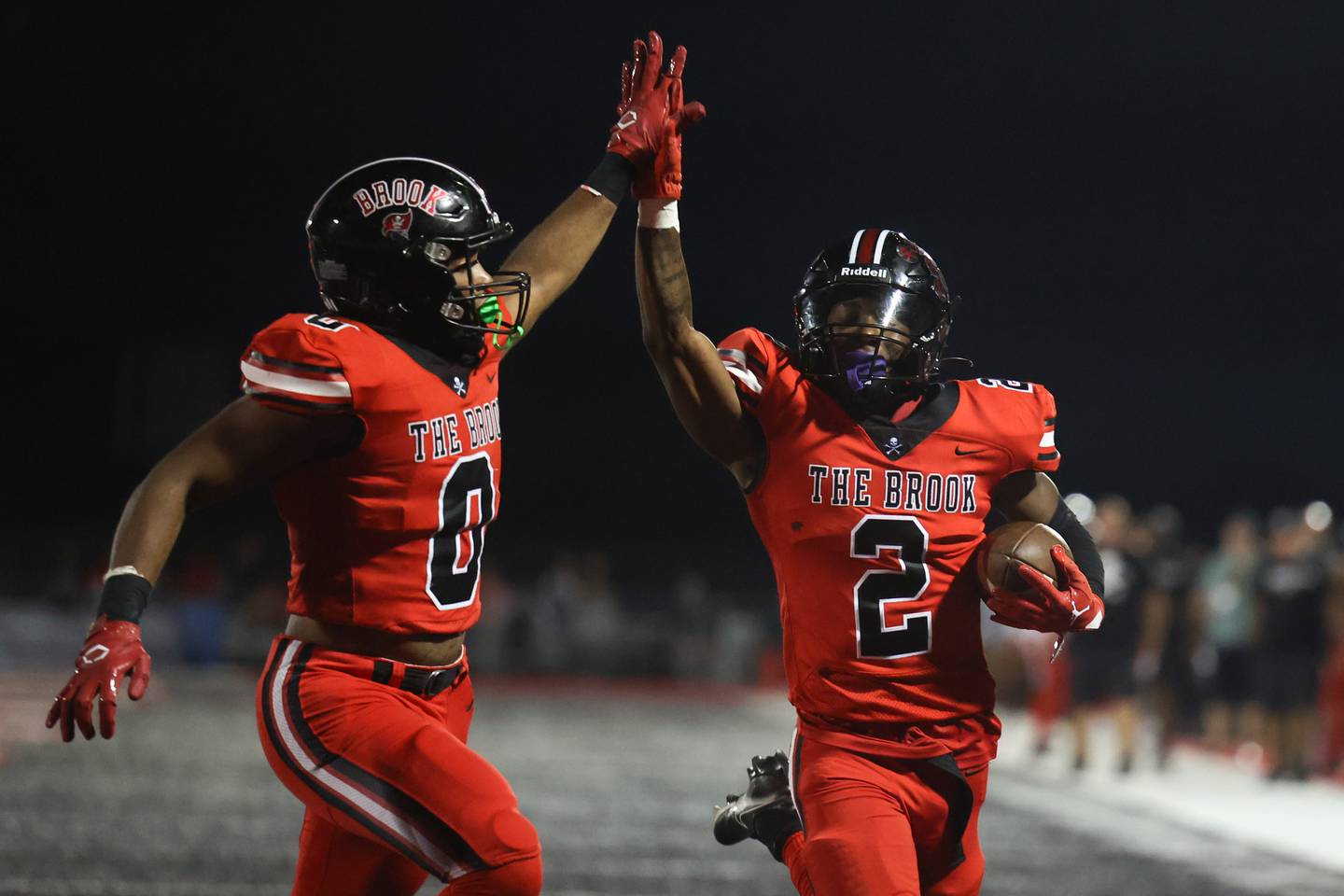 Bolingbrook’s Joshua Robinson (0) high fives Kyan Berry-Johnson (2) as he scores on a breakaway run against Minooka. Friday, Aug. 26, 2022, in Bolingbrook.