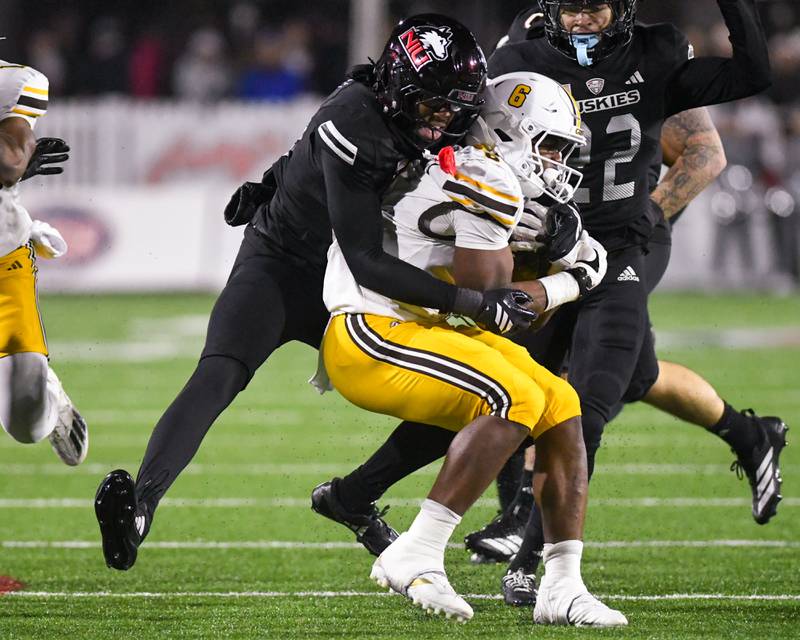 Northern Illinois University's defensive back Taylor Powell, left, wraps up Western Michigan’s ball carrier Jalen Buckley during the game on Tuesday Nov. 18, 2025, held at Huskie Stadium.