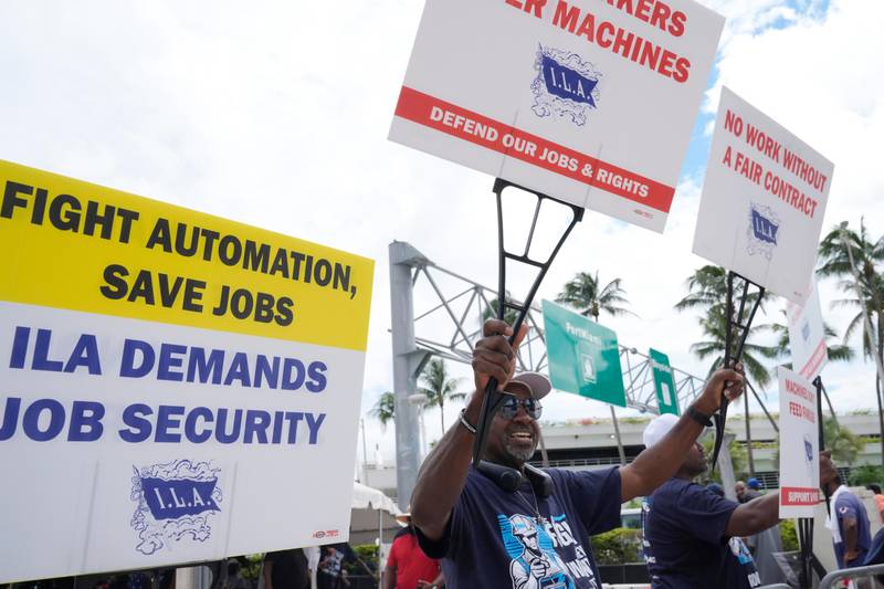 Dockworkers from Port Miami display signs at a picket line, Thursday, Oct. 3, 2024, in Miami.   (AP Photo/Marta Lavandier)