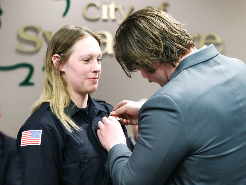 New Sycamore firefighter KeeLey Meyer has her badge pinned on by boyfriend Jake Watson after being officially sworn in by city clerk Mary Kalk Monday, April 1, 2024, during the Sycamore City Council meeting in the chambers at Sycamore Center.