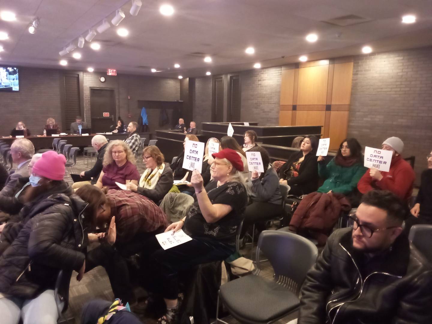 Data center opponents hold up signs at the Joliet City Council meeting on Tuesday, Jan. 20, 2026.