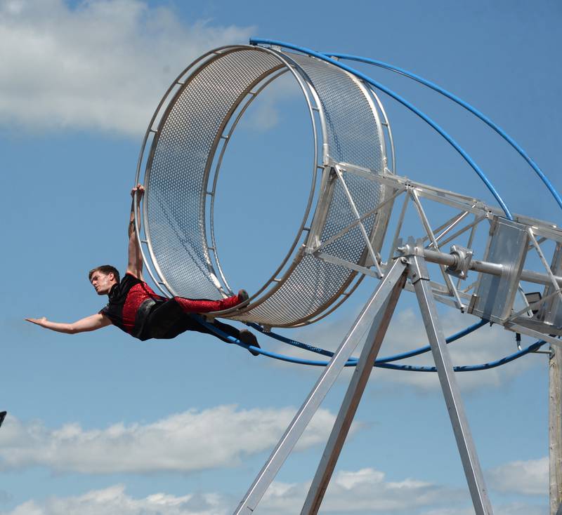 A performer with the Cincinnati Circus Thrill Show swings from the "Wheel of Death" at the Lee County Fair on Sunday, July 30, 2023.