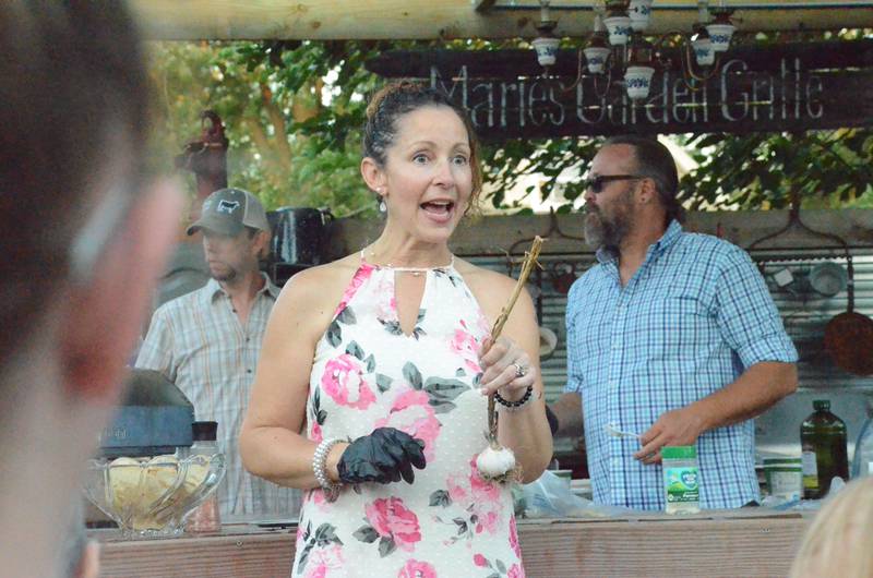Elburn garlic farmer Sharon Pferschy displays a garlic bulb at an outdoor cooking class Saturday by Marie Wilkinson Food Pantry in Aurora. Background is husband Anthony "Tony" Pferschy, class co-presenter.