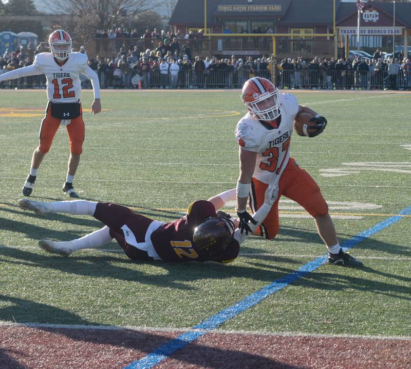 Byron's Caden Considine (37) fights to reach the goal line as Lombard-Montini's Sean Hubney grabs his jersey during 3A semifinal action in Lombard on Saturday, Nov. 18, 2023.