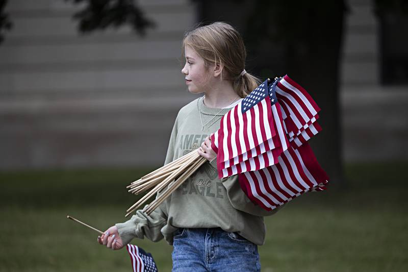 Jessica Roe, 11, looks to plant flags on the Old Lee County Courthouse lawn in Dixon Wednesday, Sept. 6, 2023. Young America’s Foundation placed 2,977 flags on the lawn of both the courthouse and the Reagan Boyhood Home.