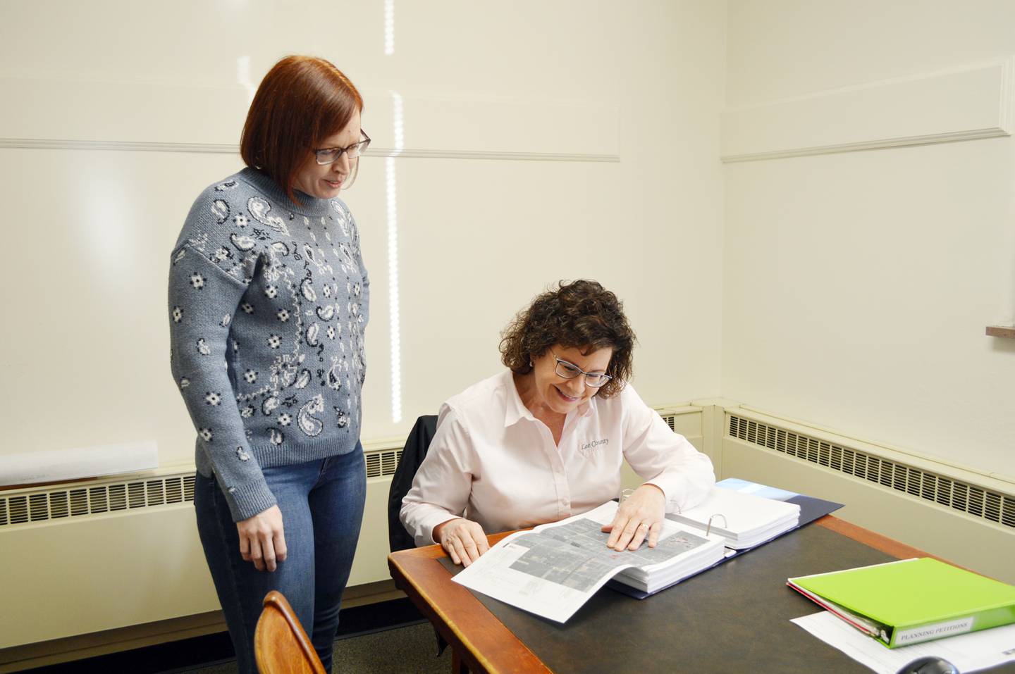 Lee County Zoning Administrator Dee Duffy, right, and Renewable Energy Coordinator Alice Henkel look at a zoning petition in this posed photo on Dec. 27, 2023. Duffy is retiring on Jan. 2, 2024, after which Henkel will take over as zoning administrator.