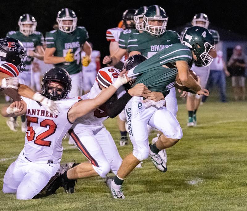 St. Bede quarterback John Brady (4) runs the ball as Erie-Prophetstown's Amen Barron (52) and Michael Collins try to bring him down on Friday, Sept. 2, 2022 in Peru.