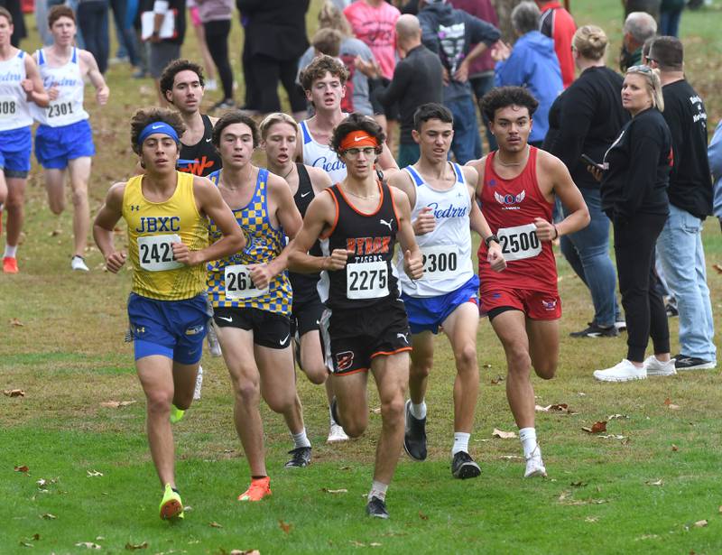 Johnsburg's Grady Smith (left), Byron's Tim Starwalt (center) and Oregon's Daniel Gonzalez (far right) run with the pack at the Amboy Columbus Day Cross Country Invitational held at Shady Oaks Country Club near Amboy on Monday, Oct. 13, 2025. Smith won the event and Starwalt finished third.