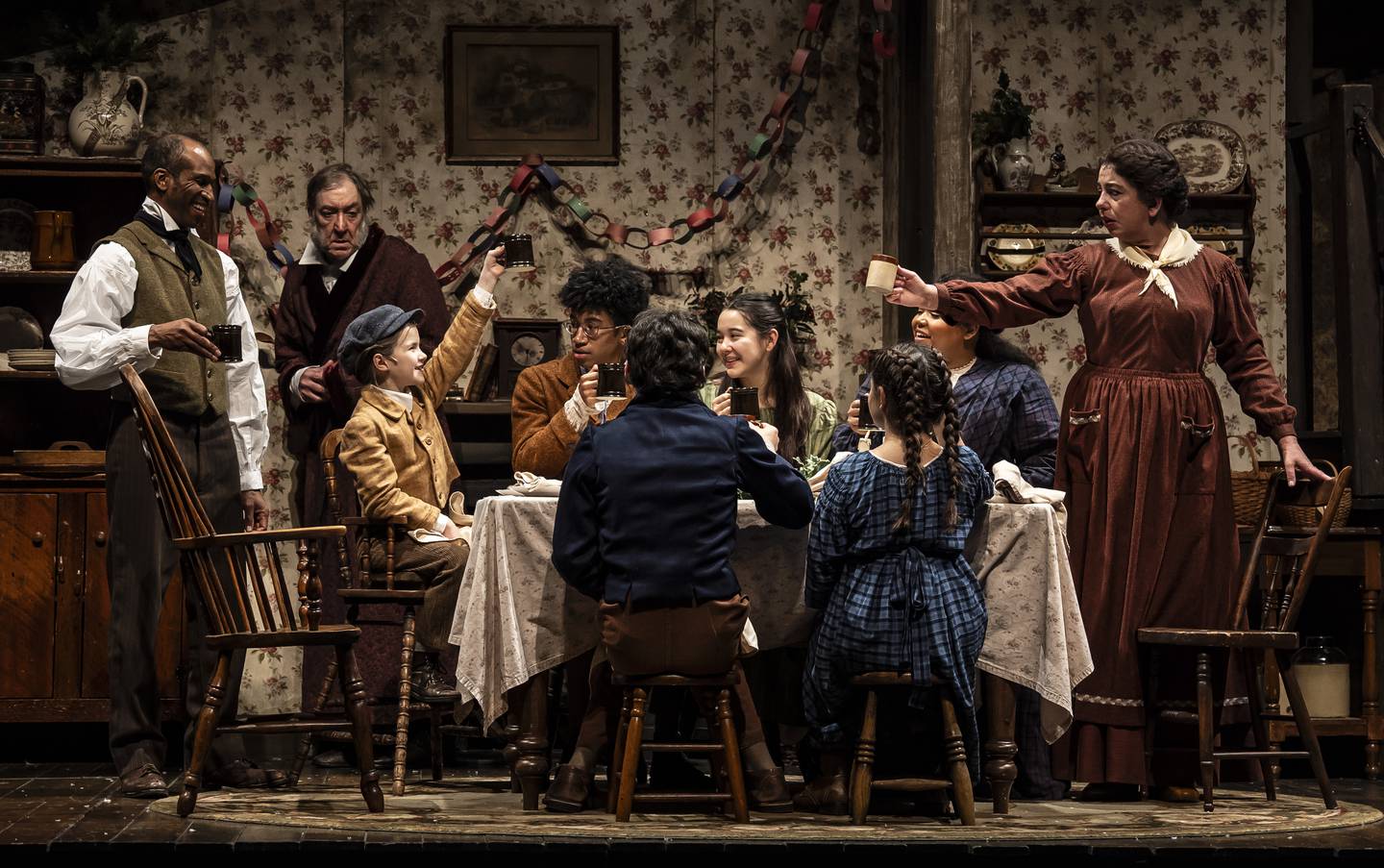 Anthony Irons (Bob Crachit, from left), Christopher Donahue (Scrooge), Ava Rose Doty of Downers Grove (Tiny Tim), Xavier Irons, Henry Lombardo, Isabel Ackerman, Viva Boresi, Tafadzwa Diener and Susaan Jamshidi in "A Christmas Carol" at Goodman Theatre in Chicago 2024.