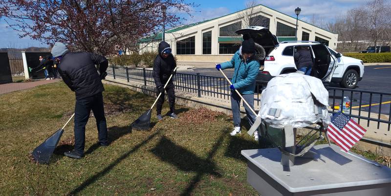 Members of the RiverGlen Christian Church in Waukesha, Wisc. rake the lawn around the Middle East Conflicts Memorial Wall in Marseilles on Wednesday afternoon.