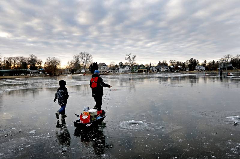 Elliot Mongeon, 10, tags along with Dylan Kowalski as Kowalski retrieves his fishing gear while ice fishing on Wednesday, Jan. 8, 2025, on the westside of Crystal Lake near the Lakewood Village Hall.