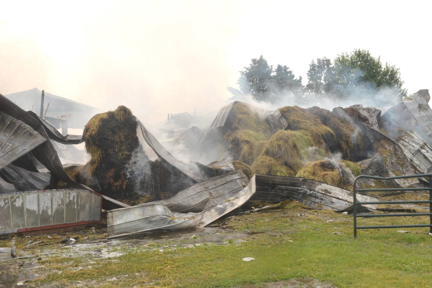 Round bales of hay smolder after a fire destroyed the large shed they were stored in north of Dixon on Friday morning.