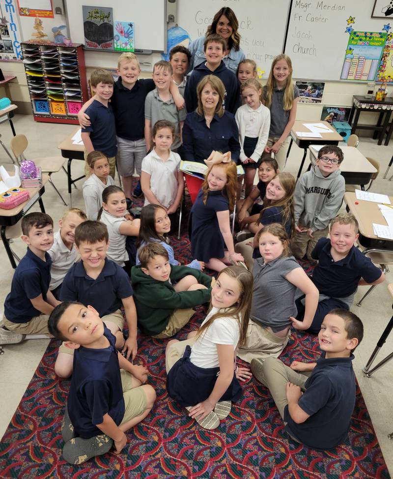Denice Melody (seated center) is retiring after 42 years in education, the last 40 with second grade at Marquette Academy Grade School. With her is her current class and teaching assistant Mary Dyche.