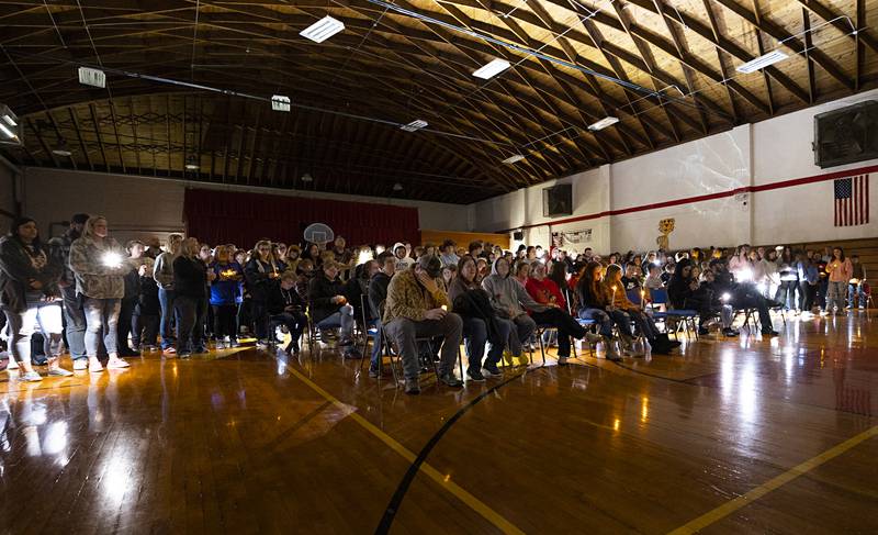 Lights from phones and flashlights illuminate the Tampico Community Center Sunday, March 31, 2024 during a vigil for three local teens who died in a Thursday collision.