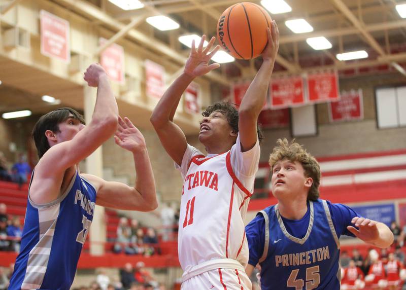 Ottawa's Hezekiah Joachim runs in the lane as he is stopped by Princeton's Noath LaPorte and teammate Luke Smith on Monday, Feb. 3, 2025 in Kingman Gymnasium at Ottawa High School.