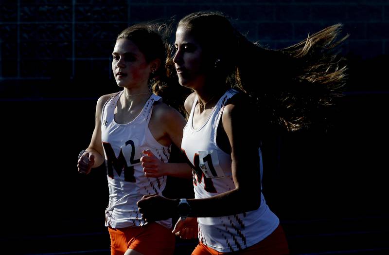 McHenry’s Danielle Jensen (right) and Skyler Balzer (left)  run together to finish the 3200 meter run in first and second on Friday, April 19, 2024, during the McHenry County Track and Field Meet at Cary-Grove High School.