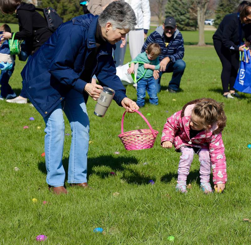 Ember Schafer, 3, finds an egg at the Elburn Lions Easter Egg Hunt while her grandmother holds her basket on Saturday, April 12, 2025 in Elburn.
