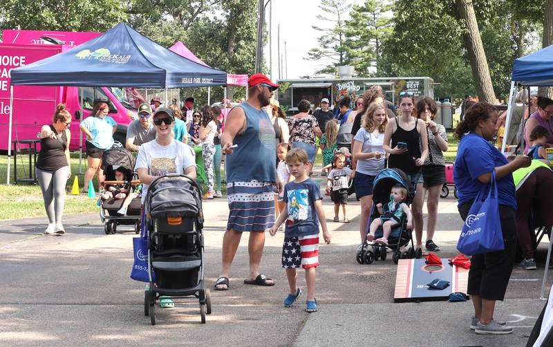 Visitors make their way through the booths Thursday, July 21, 2022, during the DeKalb Chamber of Commerce Family Fun Fest at Hopkins Park in DeKalb.