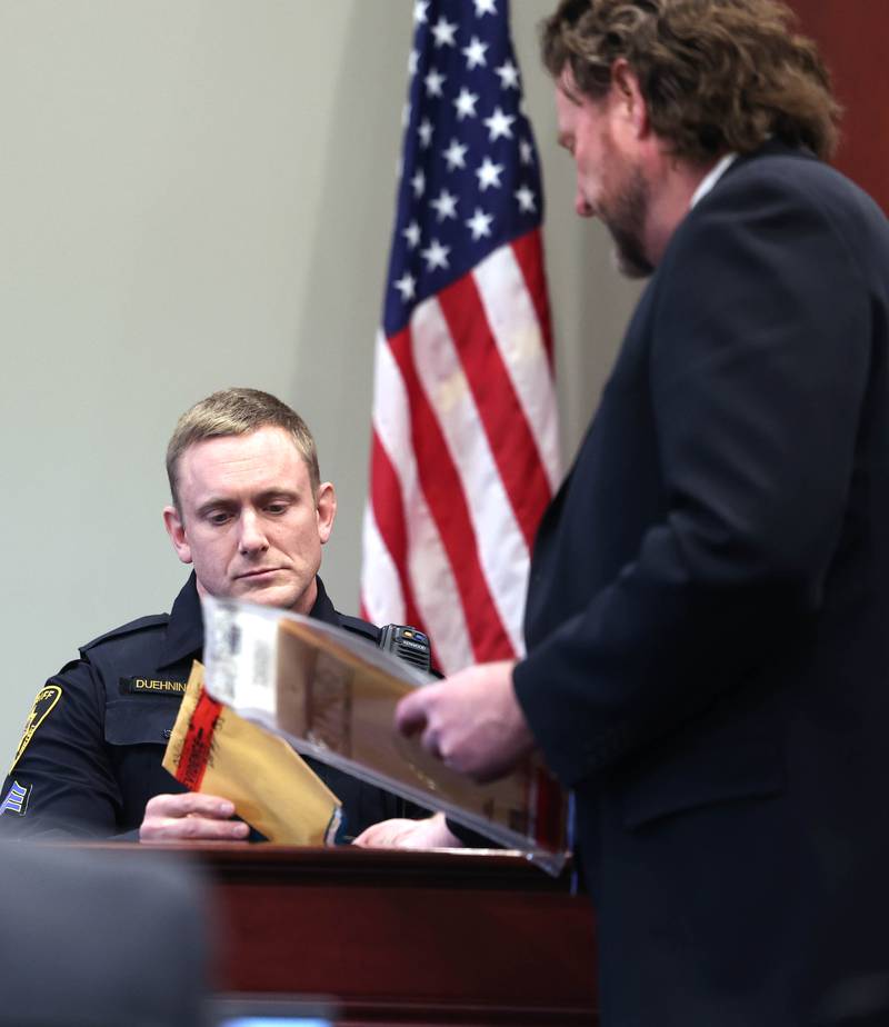 Lead prosecutor Scott Schwertley of the DeKalb County State's Attorney's Office (right) hands DeKalb County Sheriff's Detective Josh Duehning some evidence Monday, Jan. 27, 2025, during his testimony on day three of the Jonathan D. Hurst trial at the DeKalb County Courthouse in Sycamore. Hurst is charged in the 2016 slayings of Sycamore elderly mother and son Patricia and Robert Wilson.