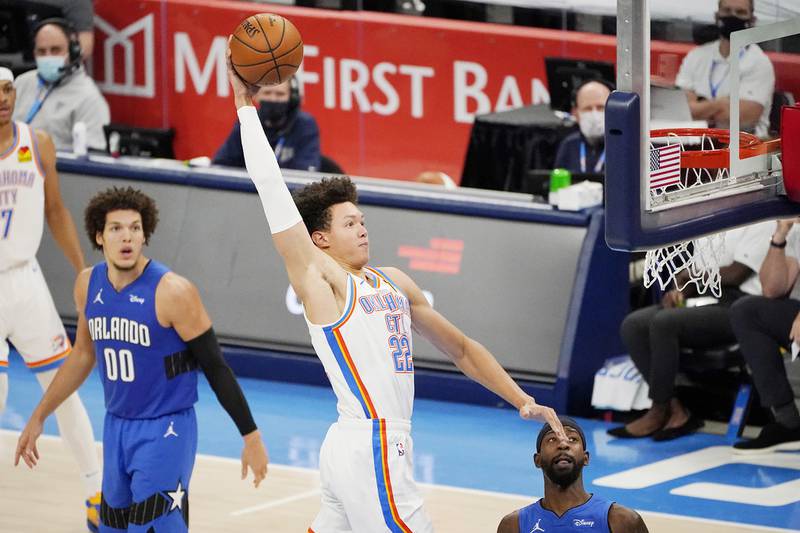 Oklahoma City Thunder forward Isaiah Roby (22) goes up for a dunk between Orlando Magic forward Aaron Gordon (00) and guard Terrence Ross during the second half of an NBA basketball game Tuesday, Dec. 29, 2020, in Oklahoma City. (AP Photo/Sue Ogrocki)