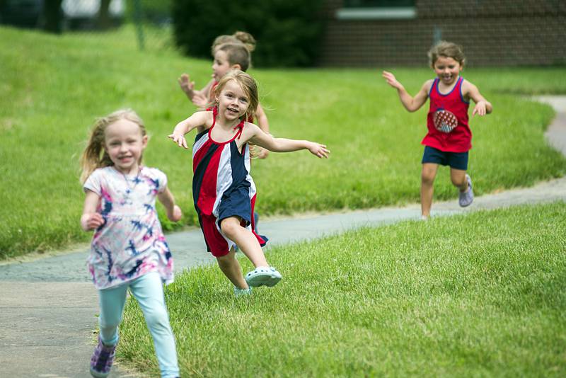 Kids excitedly file out of the building Friday, July 1, 2022 on their way to wave at the passing traffic.