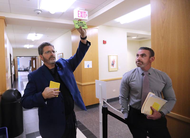 McHenry County Clerk Joe Tirio (left) asks all candidates in line if they have their “8 AM” card as McHenry County Sheriff Robb Tadelman looks on at the clerk's office in Woodstock, on Monday, Oct. 27, 2025, the first day for the Spring 2026 primary election.