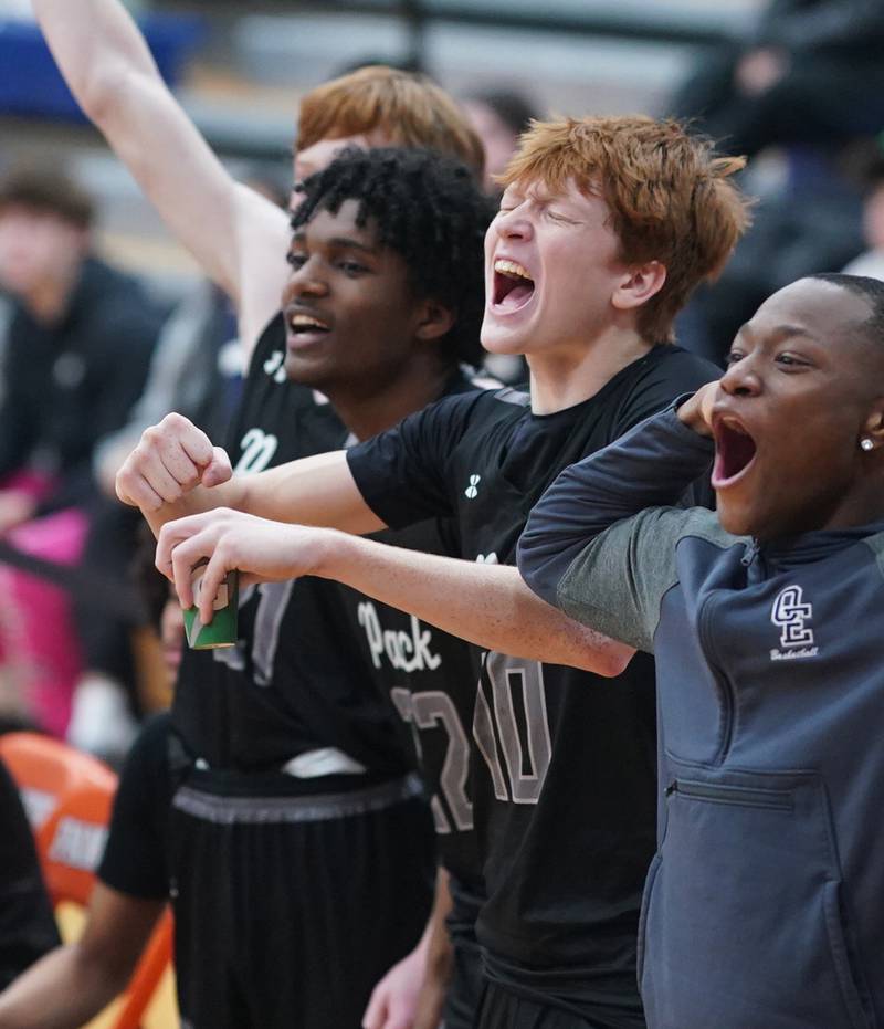 Oswego East's Noah Mason (middle) cheers on his team towards the end of the game against Oswego during a basketball game at Oswego High School on Tuesday, Dec 12, 2023.