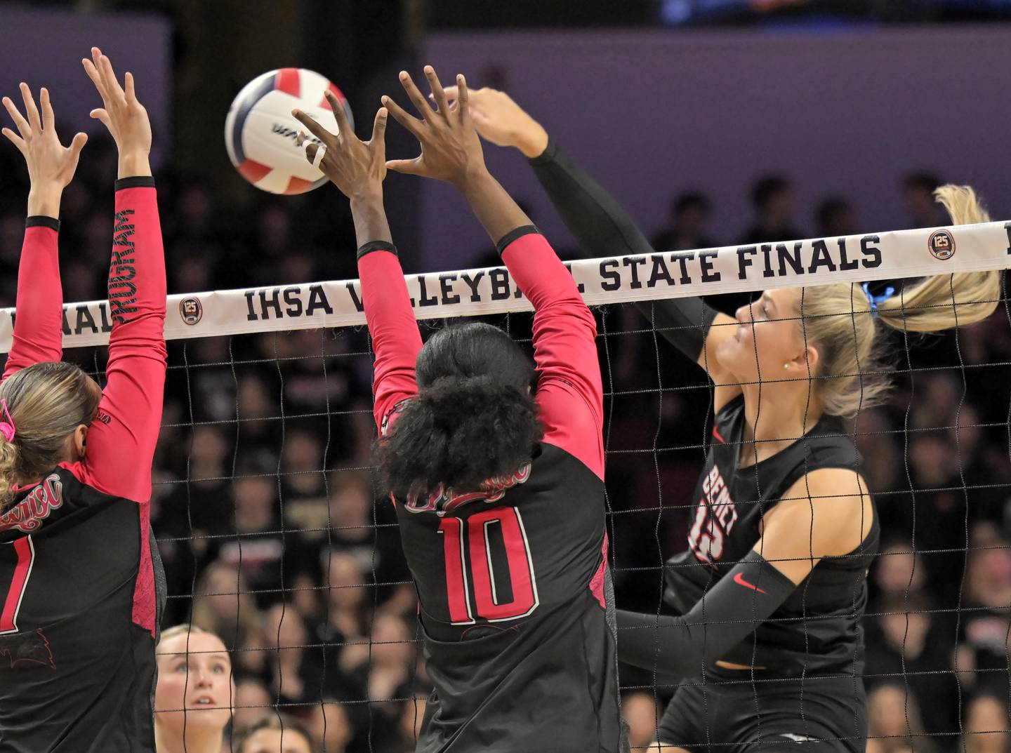 Benet’s Lynney Tarnow hits against Marist’s Tessa Dowling and Savanah Weathers in the Class 4A final match at the IHSA girls volleyball state tournament at Illinois State University on Saturday, Nov. 15, 2025