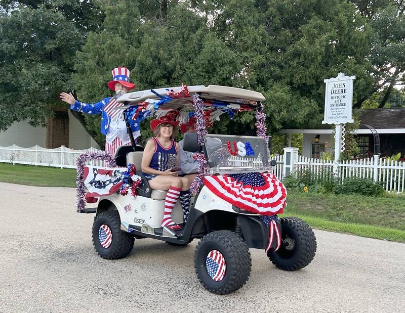 Jim Ross (Uncle Sam) and his wife, Connie (seated), lead the 7th Annual Grand Detour Golf Cart Parade on Sunday, July 6 as it passes by the John Deere Historic Site.