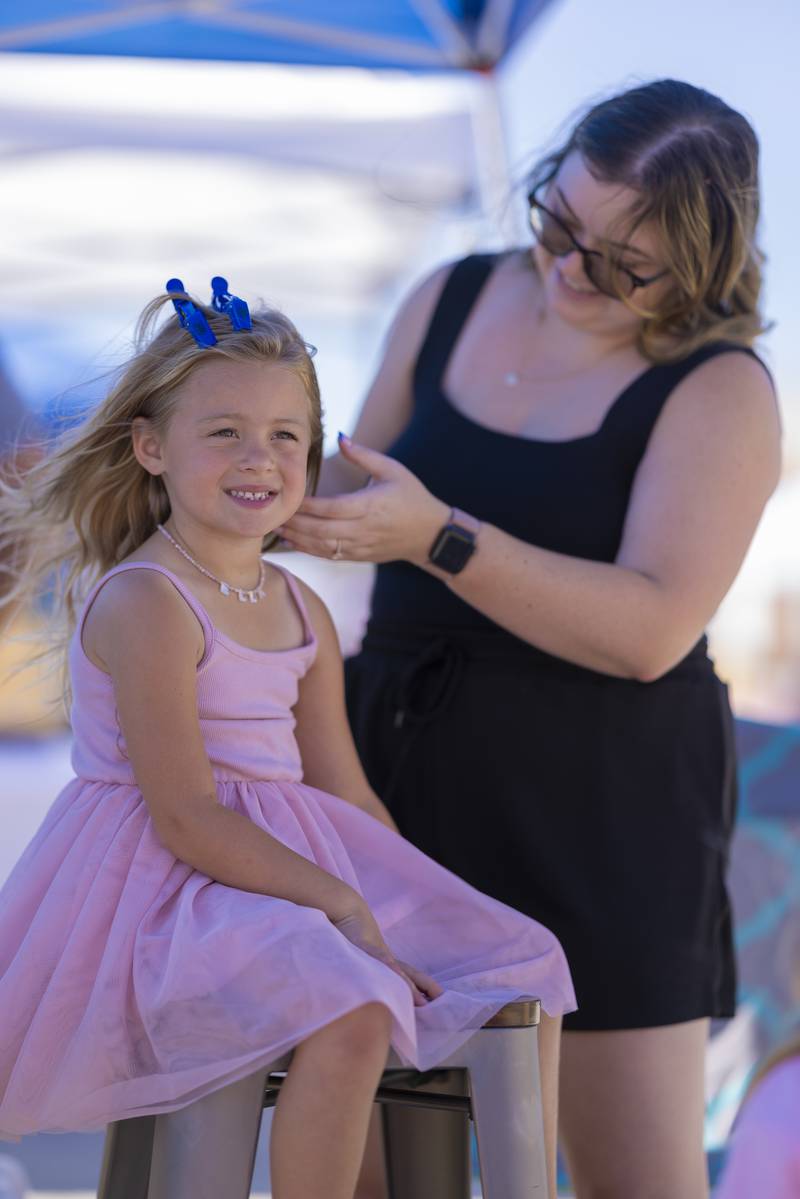 Ella Pomagier gets her hair styled with bows at one of the vendors at the Chuck Rolinski's Labor Day Bocce Tournament in  Toluca on September 1, 2024.