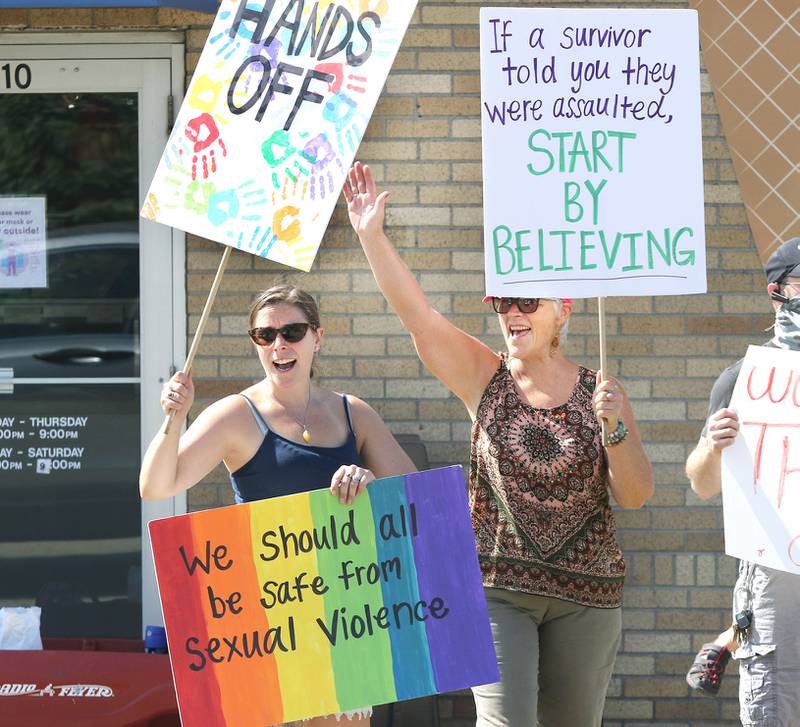 Kelsey Gettle, (left) of Sycamore, and her mom Kerry Mackenzie, from DeKalb, wave as a passing motorist honks in support during a protest in front of Shawn's Coffee Shop in Sycamore. Protesters were marching Friday to inform the public of allegations that the owner, Shawn Thrower, committed misdemeanor battery against a 15-year-old employee. Thrower allegedly bit and inappropriately touched the employee.