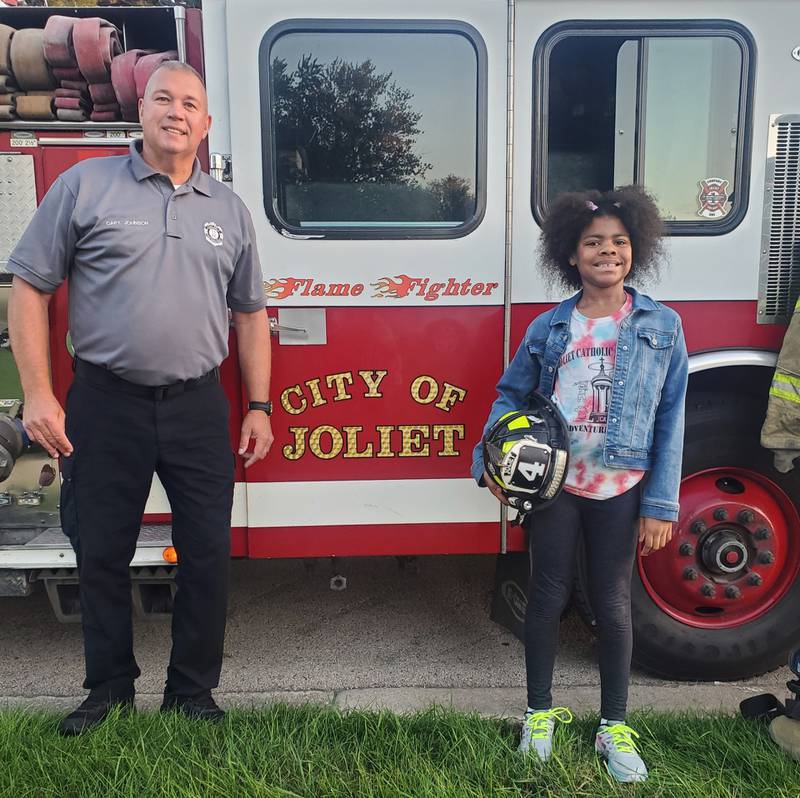 Capt. Eric Johnson of the Joliet Fire Department and Sasha Davenport, 8, of Joliet, pose for a photo on Monday, Oct. 2, 2023. Sasha won a ride to school on a Joliet Fire Department fire truck. The Joliet City Center Partnership offered the contest as part of its Kidz Fest on Aug. 5.