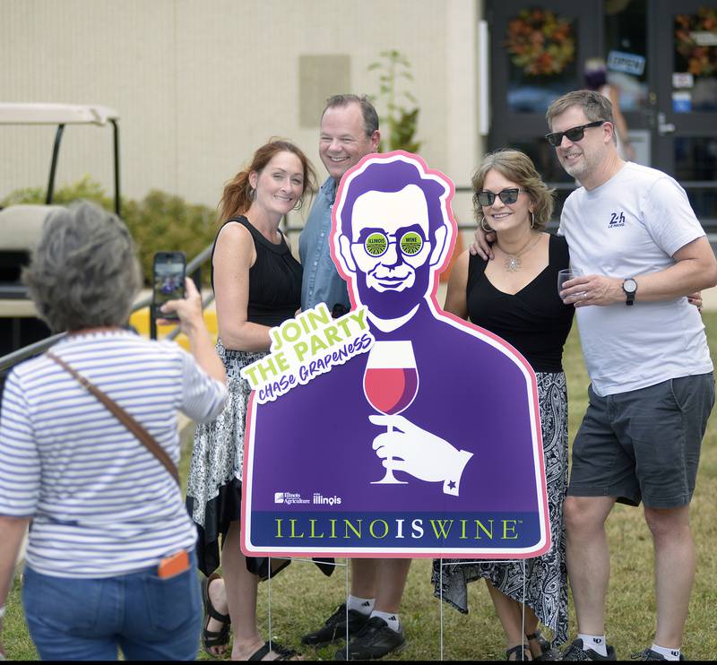 Wine Lovers pose with cutout of Abe Lincoln Saturday during the Vintage Wine Festival Saturday at Carey Memorial Park in Utica.