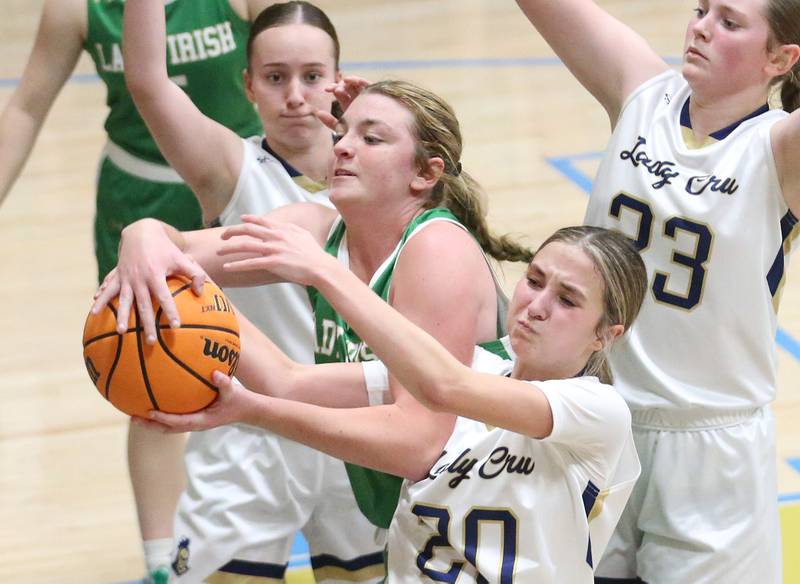Seneca's Tessa Krull grabs a rebound over Marquette's Kaitlyn Davis as teammates Chloe Larson and Kelsey Cuchra defend on Thursday, Dec. 5, 2024 in Bader Gym at Marquette High School.
