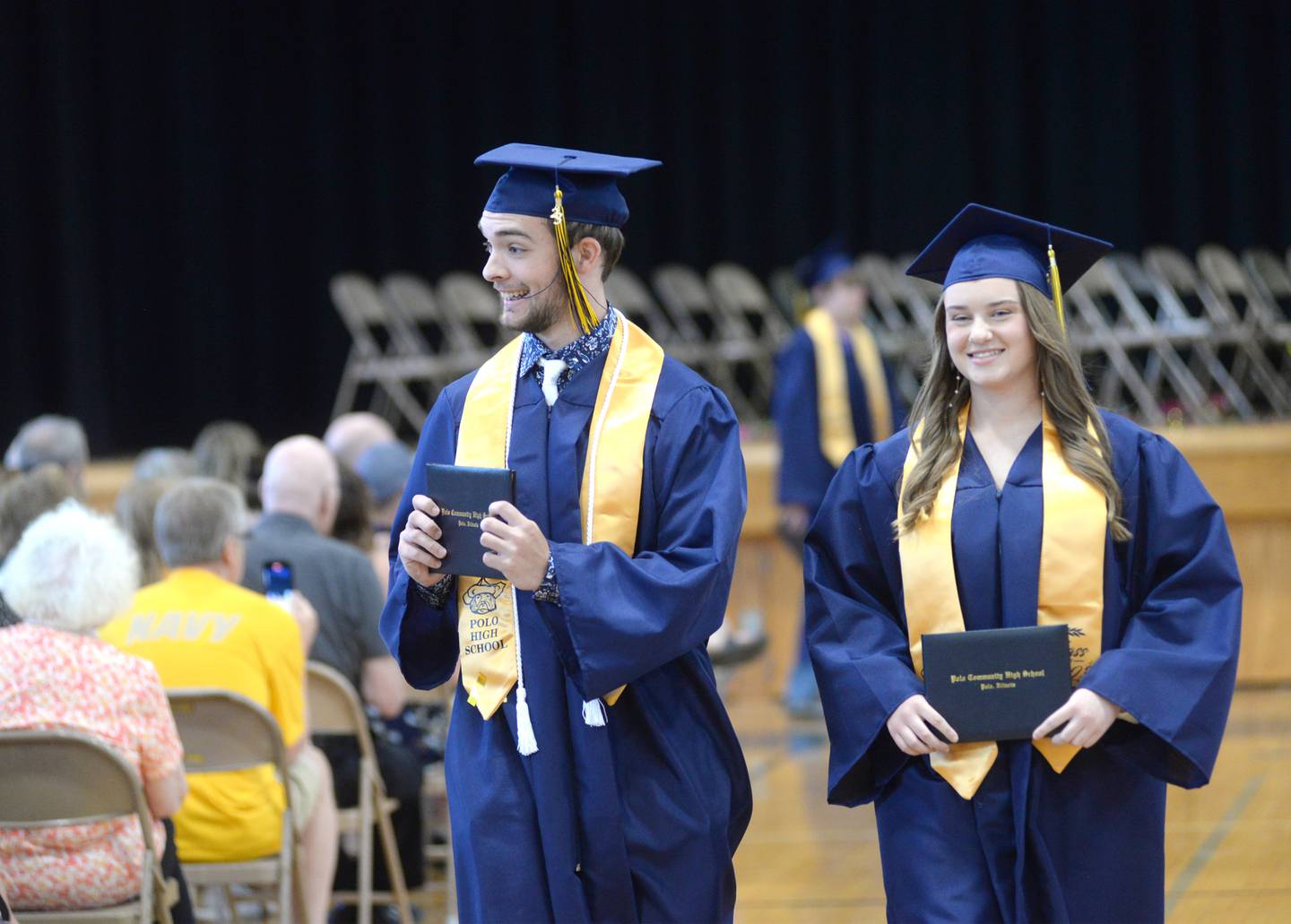 Cayden Webster smiles as he shows his diploma while exiting the Polo High School gym with Courtney Bushman at the close of commencement on Sunday, May 21.