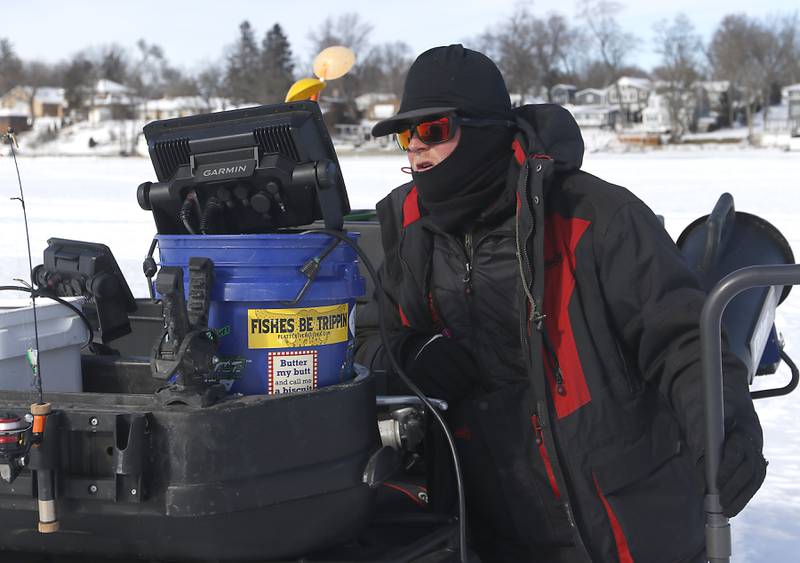 Trevor Janes, who owns Wet N Wild Outfitters, checks his fish finder while ice fishing Friday, Feb 3. 2023, on Petite Lake near Fox Lake.