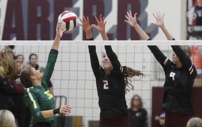 Crystal Lake South's Bobbi Wire hits the ball into the block of Prairie Ridge's Addison Smith (center) and Harleigh Serpico (right) during the IHSA Class 3A Prairie Ridge Regional championship volleyball match on Thursday, Oct. 30, 2025, at the Prairie Ridge High School in Crystal Lake.