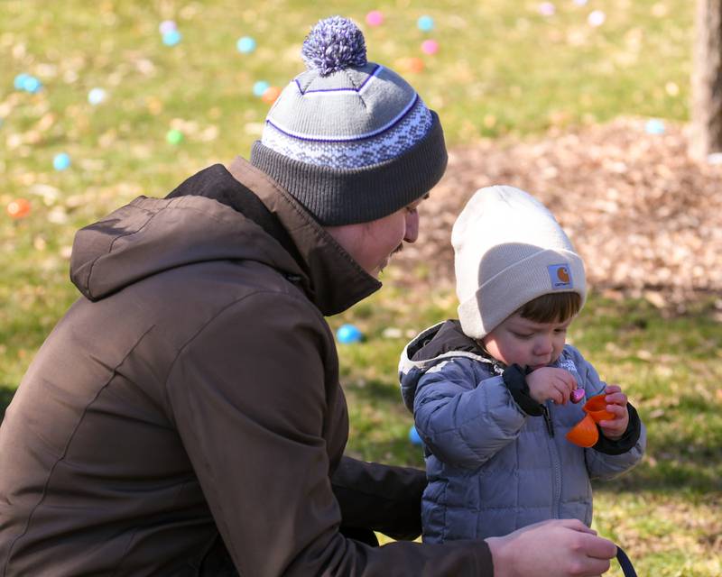 Jorge Trejo watches his son Mateo Trejo, 18 months , of Cortland, as he checks out the content of his eggs during the DeKalb Park District's annual children's egg hunt at Hopkins Park in DeKalb on Saturday, March 23, 2024.