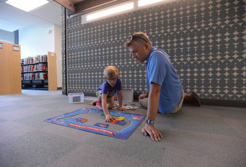 Charles and Blake Swaar of Bloomington work on a puzzle while attending the La Grange Park Library Grand Reopening Saturday Aug 3, 2024.