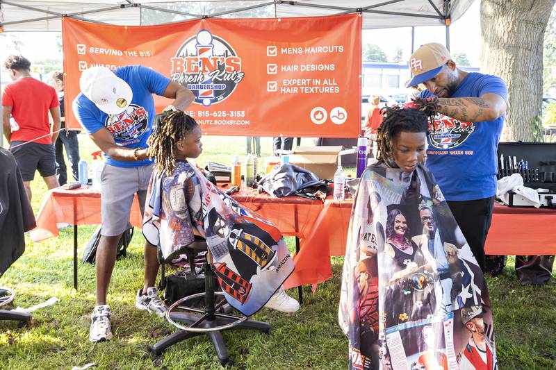 Ja’myrin (left), 8, and Ja’myree Jones, 7, get hair cuts at the Ben’s Phresh Kutz booth Tuesday, August 5, 2025, at Sterling’s National Night Out. The barber shop offers discounted cuts for students to look spiffy going back to school.