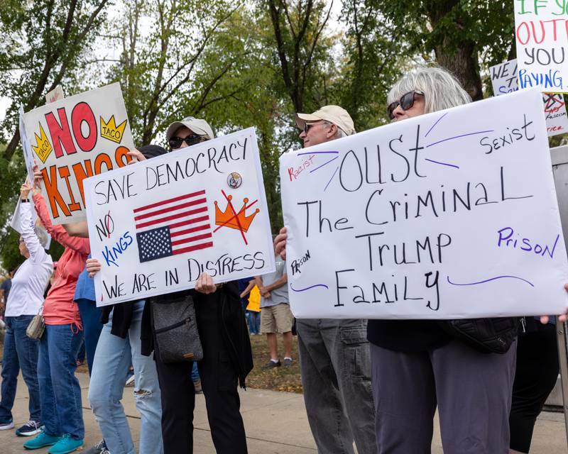 Protesters hold signs in spirit of the ‘No Kings 2.0’ Protest on Saturday, October 18, 2025 at Washington Square Park in Ottawa.
