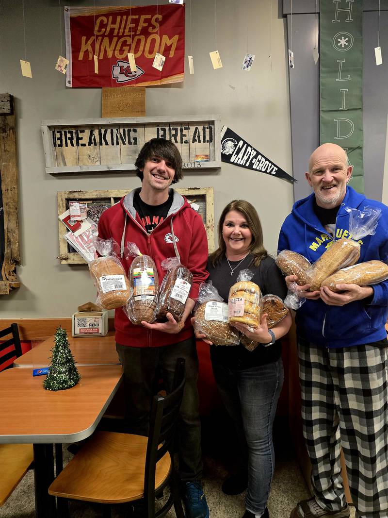 Cary-based Breaking Bread owners (from left to right) John, Teri and Chris Plazak hold loaves of bread that they will be giving away for free before Christmas.