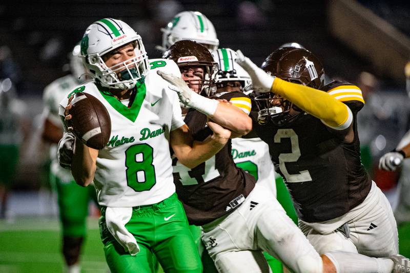 Joliet Catholic Academy's Vince Skedel and Kingston Dunagan take down Niles Notre Dame's Eric Couper during a game on Friday Oct. 3, 2025 at Busey Bank Field in Joliet