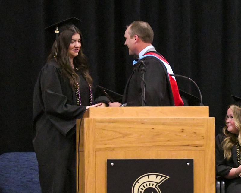 Sycamore High School Principal Brian Swanson gives senior class President Norah Chami her diploma before she reads the names of fellow classmates during the Class of 2026 Commencement on Sunday, May 24, 2026, held at the high school fieldhouse.