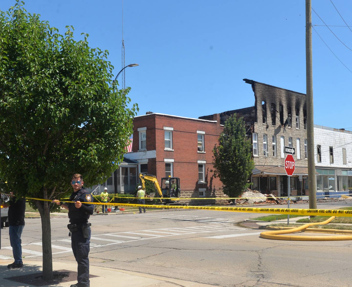 A police officer tapes off Fourth Avenue at 11:30 a.m. Friday following an early morning fire at 406 East Third Street in Sterling.