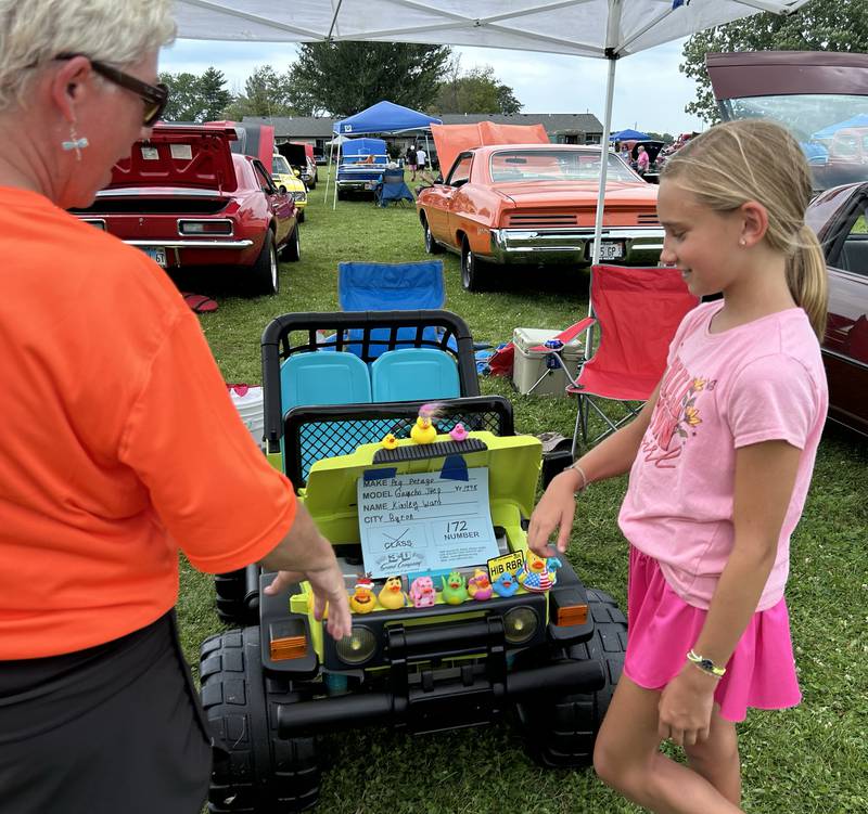 Kinsey Ward, 10, of Byron, talks to a Hib Reber Memorial Car Show committee member about her 1998 Gaucho Jeep that she entered in the show during ByronFest on Saturday, July 13, 2024 in Byron.