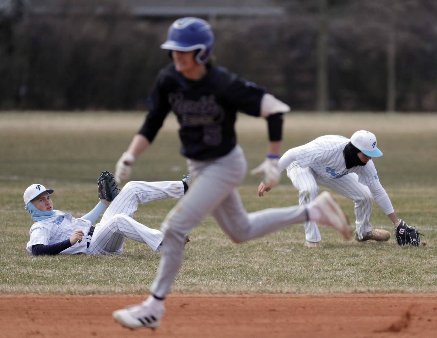 Prospect's Jack Friar (11) and Gavin Flanagan (9) pick up a shot by St. Charles North's Jaden Harmon (5) as he rounds first base and heads to second Tuesday March 28, 2023 in Mt. Prospect.