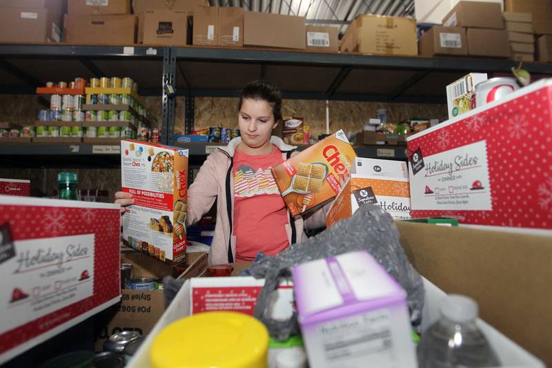 Riley Pimpo, 11, a volunteer, puts boxes of cereal into boxes for patrons to pick up at the P.L.A.N. Food Pantry in Round Lake Beach.