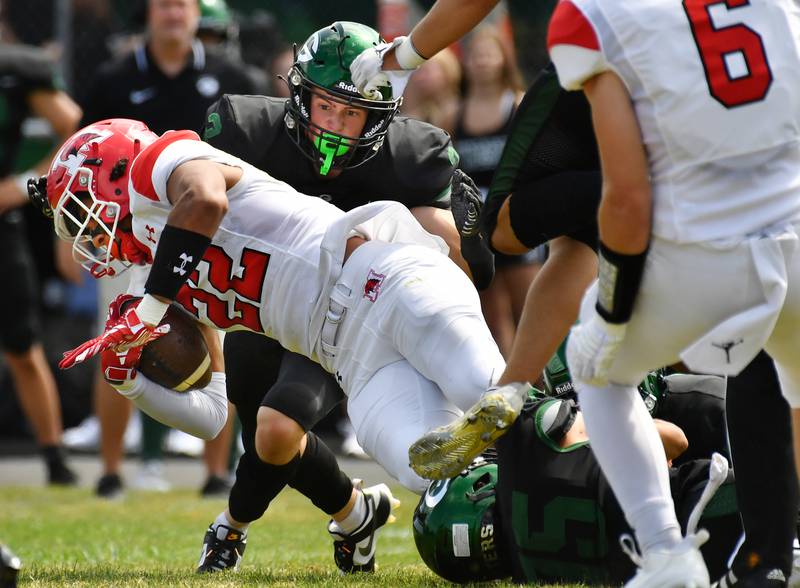 Marist's Marc Coy (22) lunges for extra yardage as Glenbard West's Aidan Murphy (2) moves in during a game on Aug. 26, 2023 at Glenbard West High School in Glen Ellyn.