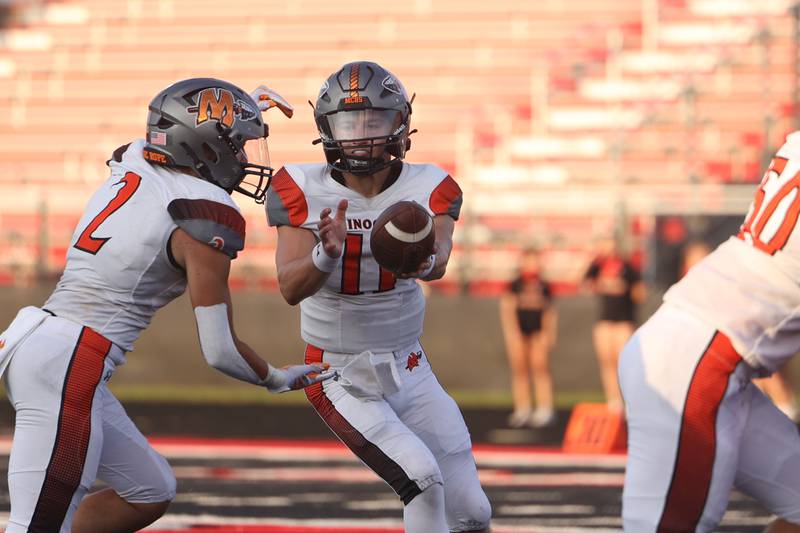 Minooka’s Joseph Partridge takes the hand off from Gavin Dooley against Bolingbrook. Friday, Aug. 26, 2022, in Bolingbrook.